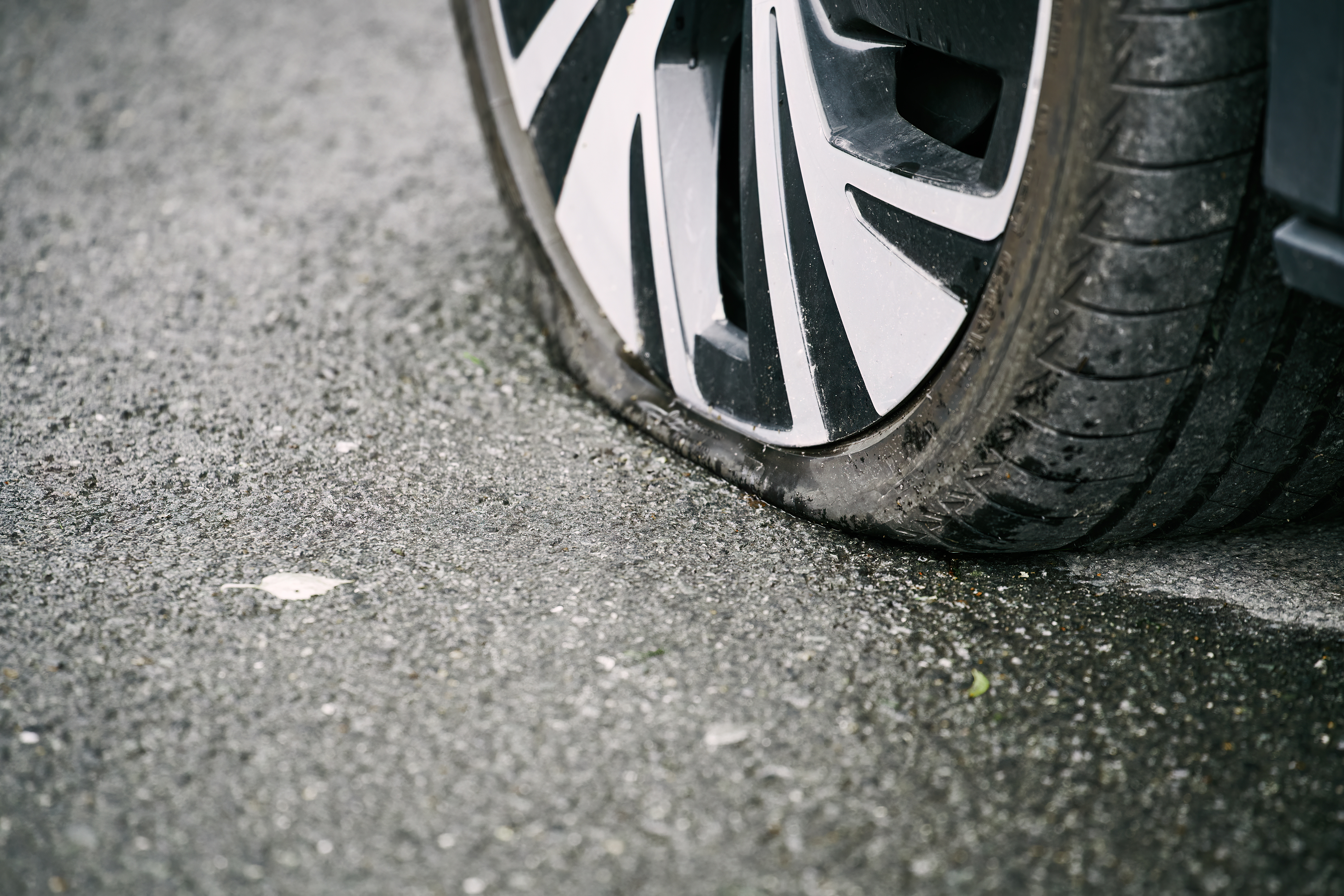 Close-up of car wheel with white and black alloy rim on asphalt pavement